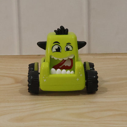 Child playing outdoors with a green cartoon monster push back car toy.